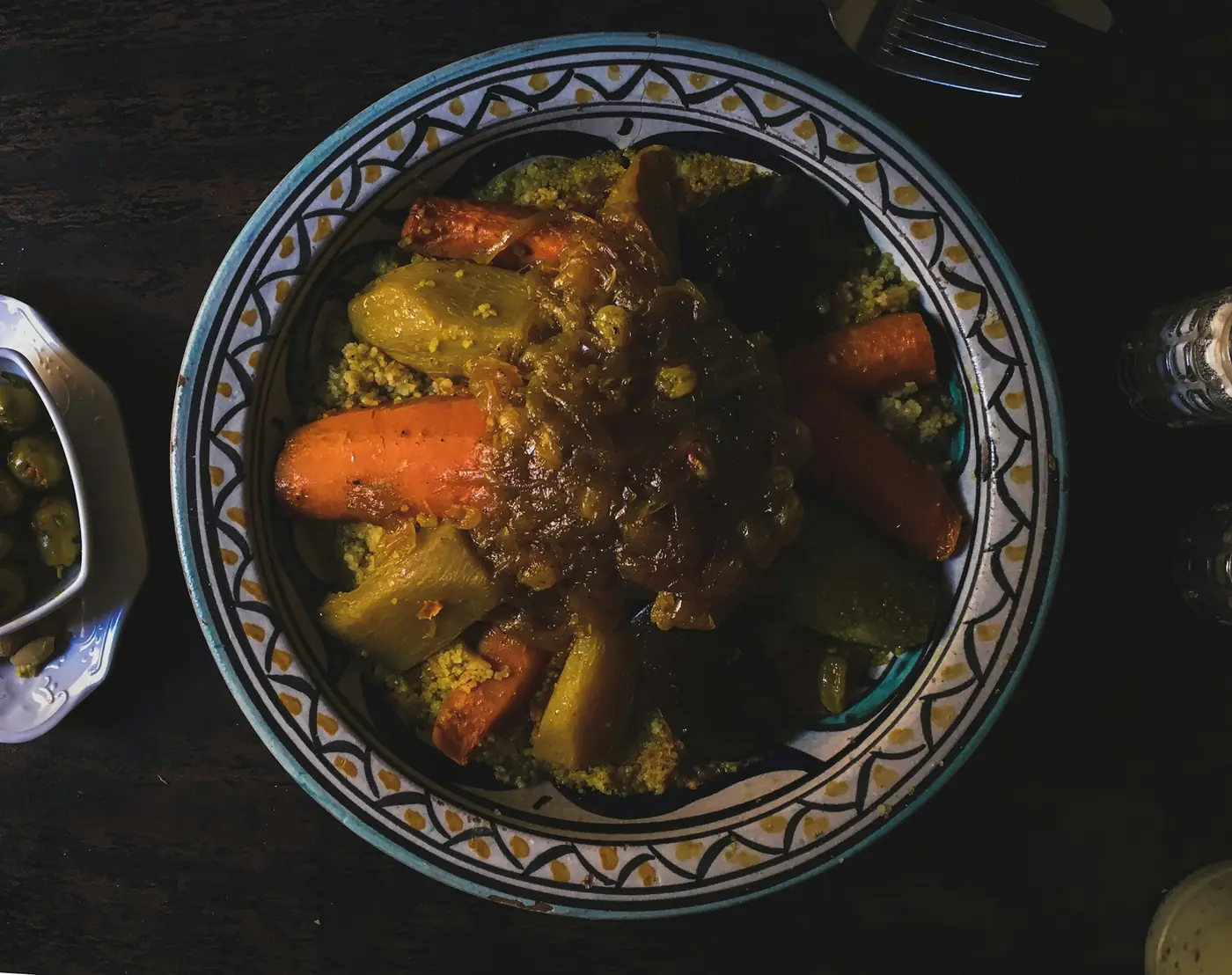 Couscous topped with carrots, courgette and meat in a patterned bowl